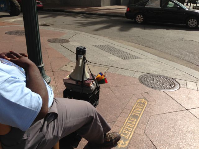 a bull horn, a Bible, a radio, and a plastic milk crate preaching in the street