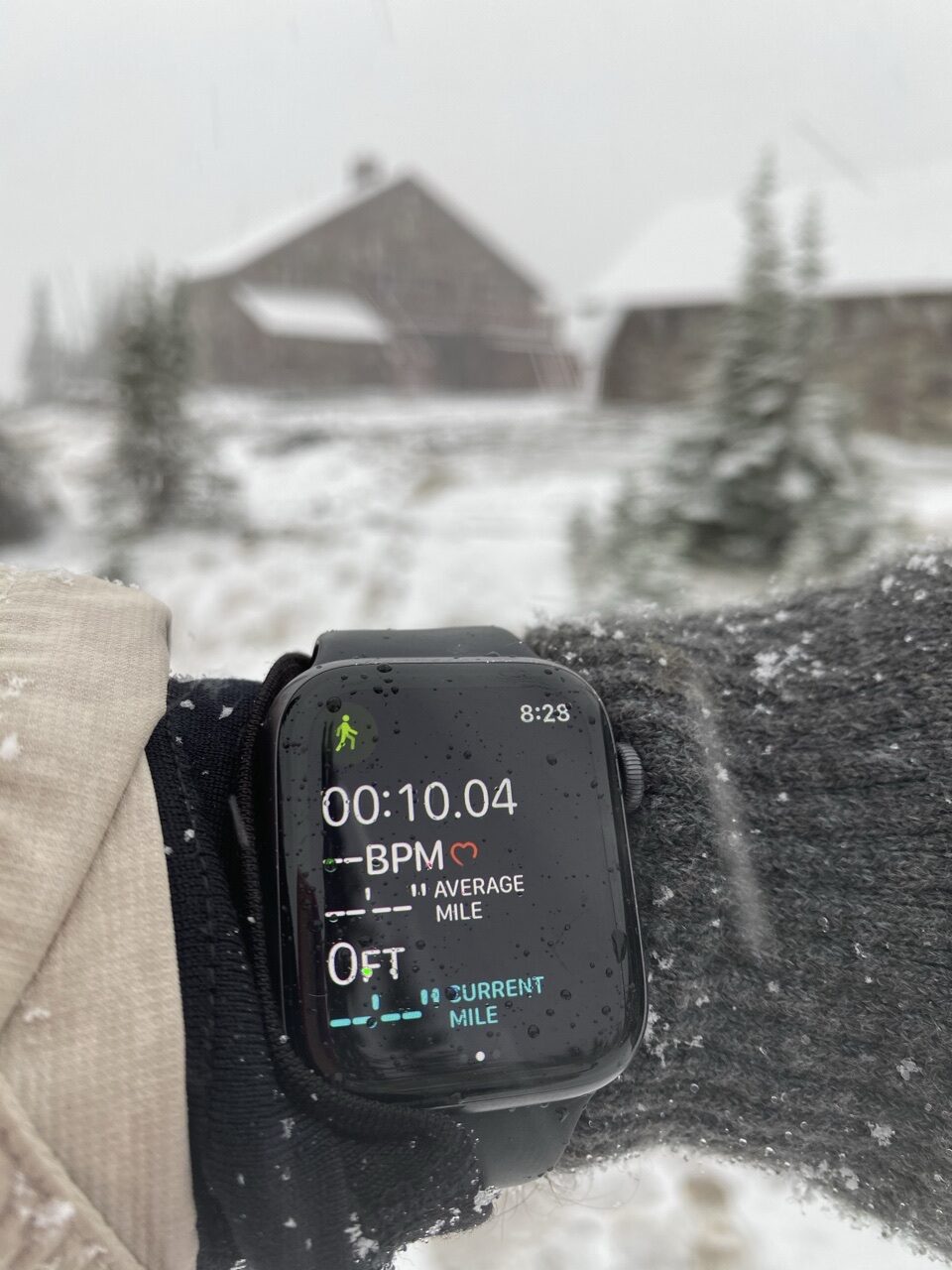 AppleWatch in foreground with mountain chalet in background during snow storm