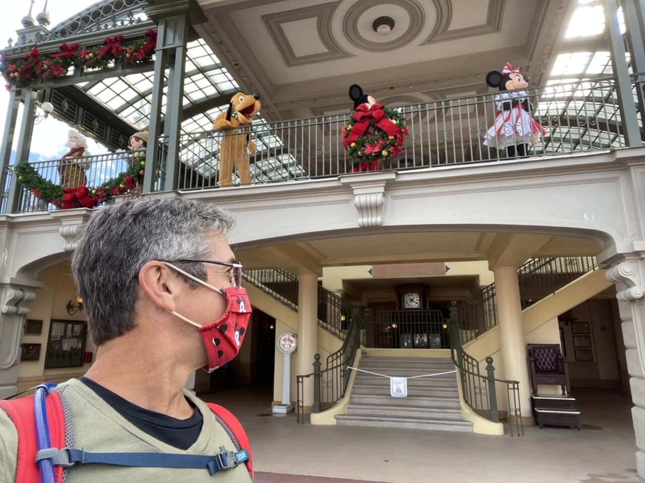 Man wearing mask with Disney characters behind him on Train Station second level