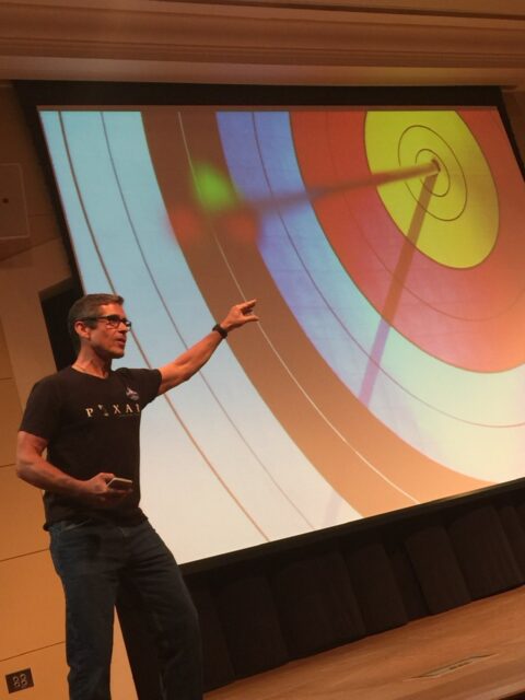 Man on a stage with a giant archery target slide