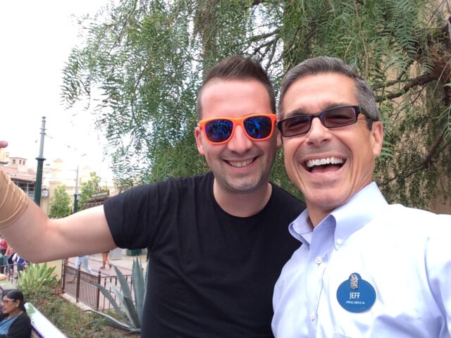A guest and Disney cast member smiling and posing for a photo