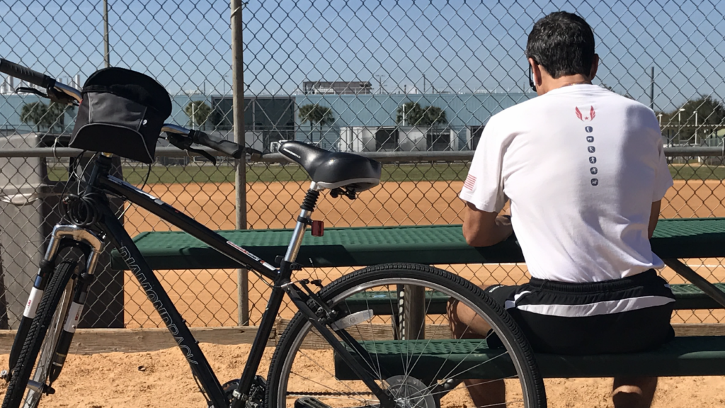 Man with back turned, sitting next to bicycle