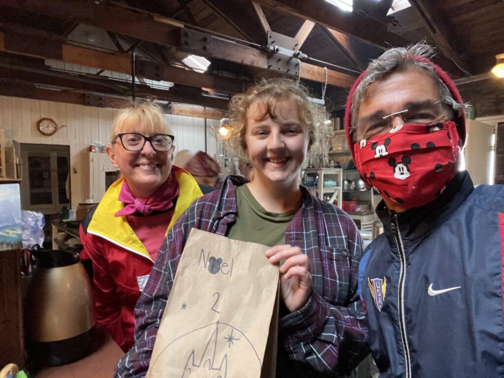 Three adults smiling with a brown lunch bag art