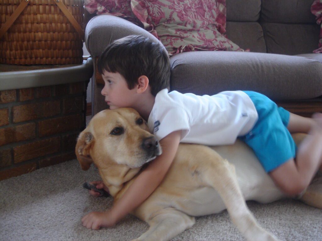 young boy laying on big dog