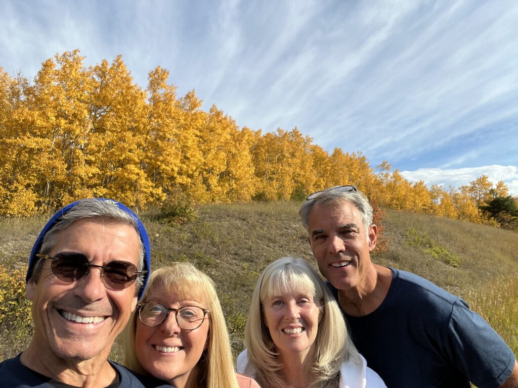 Four people standing in front of yellow fall foliage