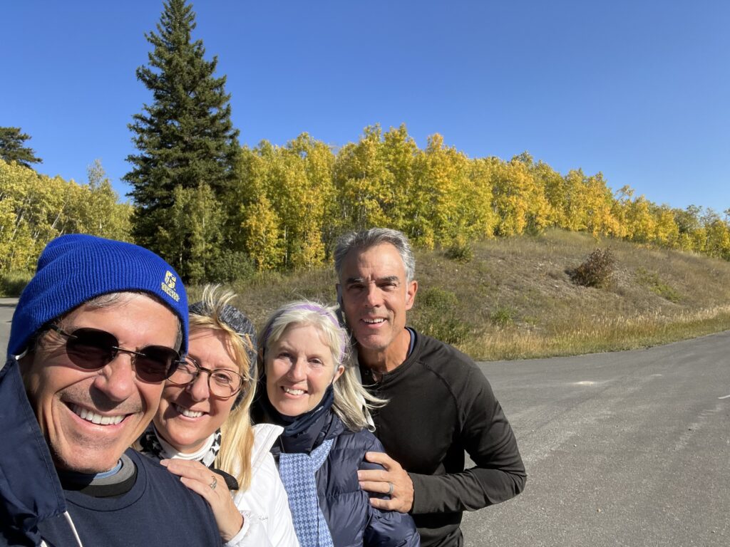Four people standing near fall foliage trees