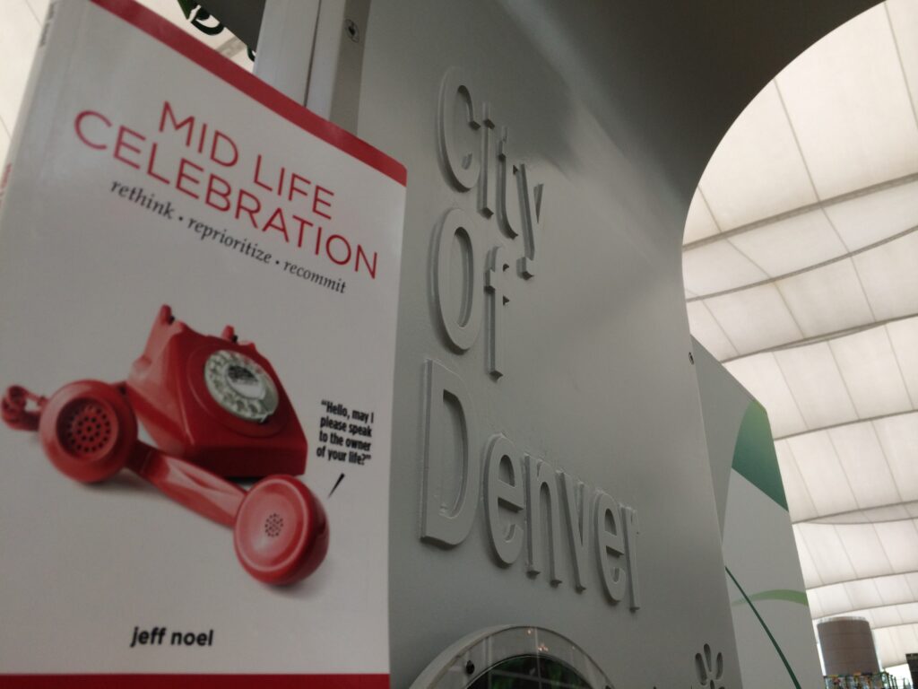 Denver airport sign and Mid Life Celebration, the book